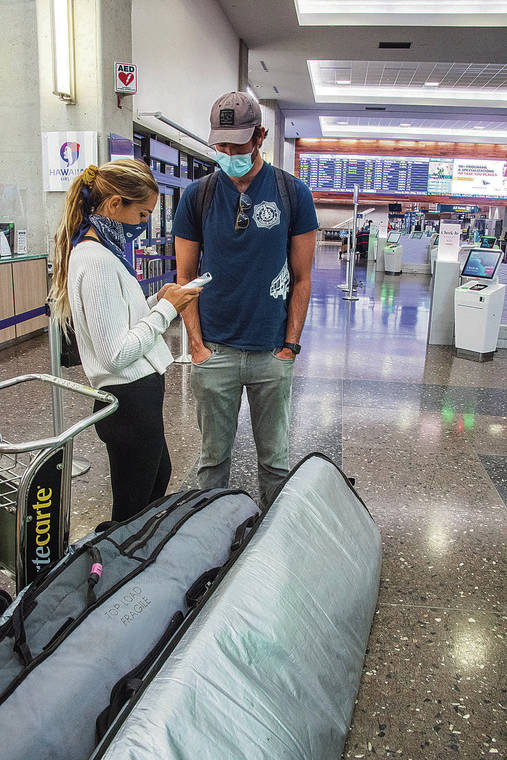 CRAIG T. KOJIMA / CKOJIMA@STARADVERTISER.COM 
                                Lindsey De Vine, left, and Brodie Martin of San Diego checked for flight information Friday at Hawaiian Airlines terminal en route home after surfing in Hawaii on their vacation.