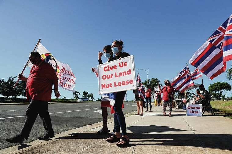 JAMM AQUINO / 2020
                                Sen. Kurt Fevella, left, and Laie residents Malakai Vendiola, 14, and mother Lahela Keliikuli hold signs and flags while joining others during a protest on Tuesday, in Kapolei. Opponents of the DHHL proposal to pursue a casino resort on DHHL land gathered ahead of the Hawaiian Homes Commission vote on the issue.