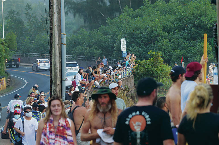 JAMM AQUINO / JAQUINO@STARADVERTISER.COM
                                People who flocked to Waimea Bay on the North Shore to watch hazardous high surf Saturday were not social distancing, and only a few wore masks.