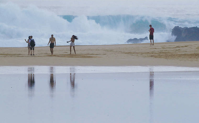 JAMM AQUINO / JAQUINO@STARADVERTISER.COM
                                Beach-goers watch huge waves at Waimea Bay Saturday. Lifeguards repeatedly have warned the public to stay off the beach in areas under a high surf warning.
