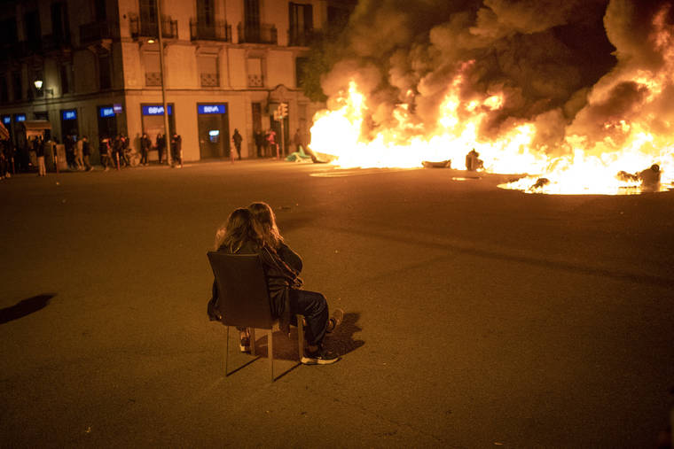 ASSOCIATED PRESS / FEB. 19
                                Two woman sit on a chair in front of burning barricades made by demonstrators during a protest condemning the arrest of rap singer Pablo Hasél in Barcelona, Spain. Violent street protests over the imprisonment of a rapper have erupted for a fourth straight night in Spain. Police in the northeastern region of Catalonia said some protesters pelted officers with bottles, stones, fireworks and paint on Friday.