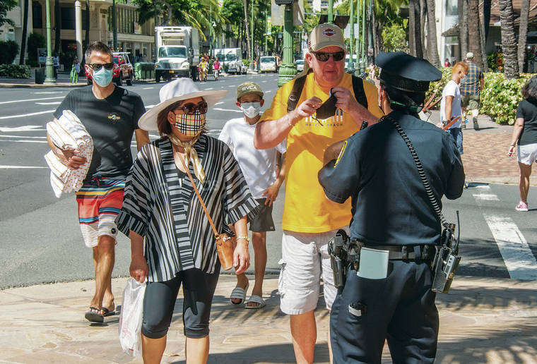 Craig T. Kojima / CKOJIMA@STARADVERTISER.COM
                                Honolulu police were out in force Thursday in Waikiki, enforcing the city’s mask mandate. Officer Justin Nakakuni warned a pedestrian on Kalakaua Avenue who quickly complied.
