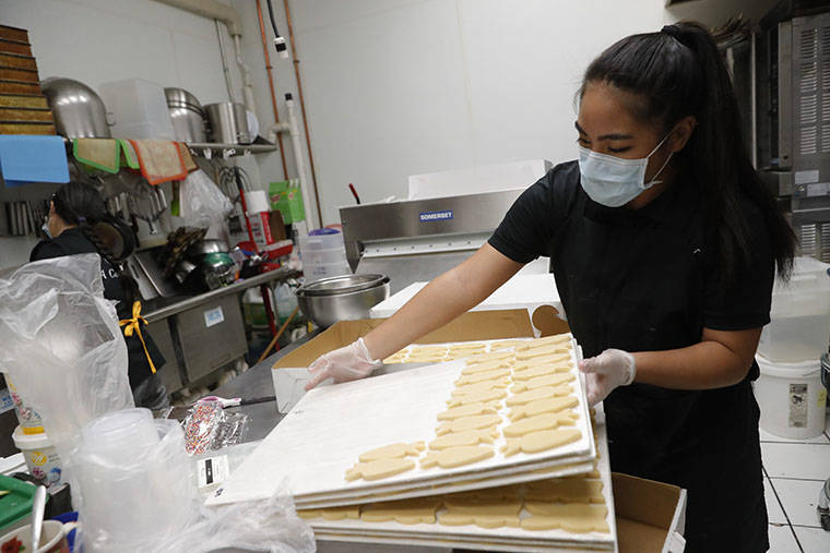 JAMM AQUINO / APRIL 3
                                A Cake Life boutique bakery worker Tiffany Waikiki checks on Easter cookies. The award-winning custom cake shop is among thousands of vendors in Hawaii’s wedding industry whose businesses have been hit hard due to the coronavirus pandemic.