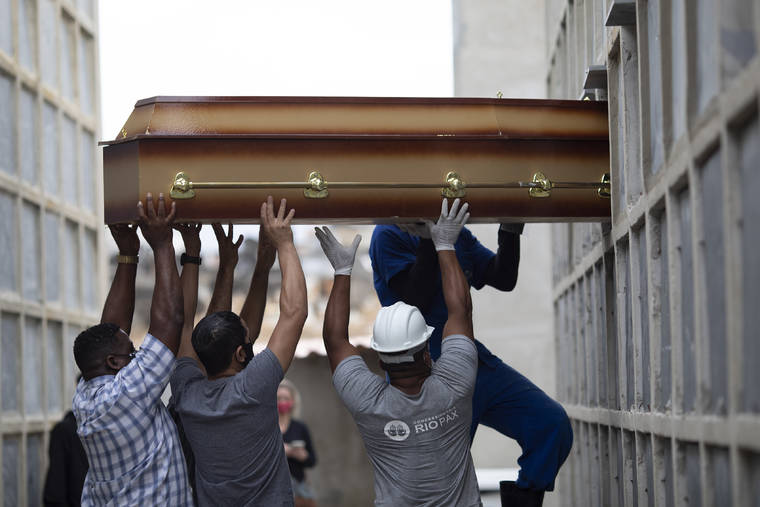 ASSOCIATED PRESS
                                The remains of a woman who died from complications related to COVID-19 are placed into a niche by cemetery workers and relatives at the Inahuma cemetery in Rio de Janeiro, Brazil, on Tuesday.