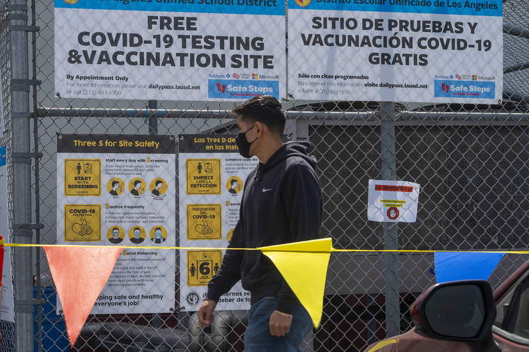 ASSOCIATED PRESS
                                Gustavo Cano, 21, who has already been vaccinated, reads a banner with the “Safe Steps to Safe Schools” instructions before getting a free test at a COVID-19 testing and vaccination site set up by the Los Angeles Unified School District in East Los Angeles on April 15.