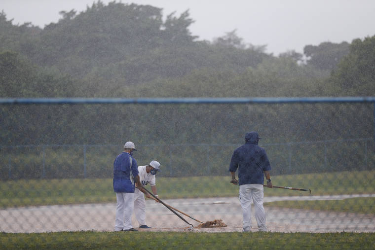 JAMM AQUINO / JAQUINO@STARADVERTISER.COM
                                Kailua High School baseball coaches tend to a flooded field as this afternoon’s OIA baseball game against the Kalani Falcons was called off due to the weather.