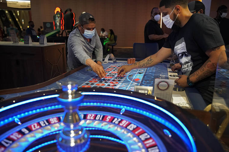 ASSOCIATED PRESS
                                People wore face masks, in July 2020, as a precaution against the coronavirus as they played roulette on the Fourth of July at the Strat hotel-casino in Las Vegas. Some Las Vegas Strip casinos have been allowed to open at 100% capacity, officials said today, after showing Nevada state regulators that at least 80% of their employees have received at least one shot of coronavirus vaccine.