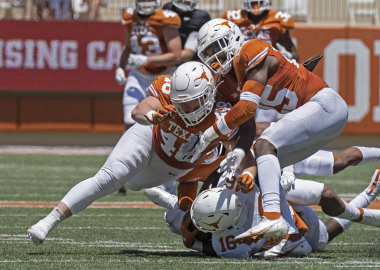 ASSOCIATED PRESS / APRIL 24
                                Texas defenders Jake Ehlinger, left, and B.J. Foster, right, tackle Kayvontay Dixon (16) during the first half of the Orange and White spring scrimmage college football game in Austin, Texas.