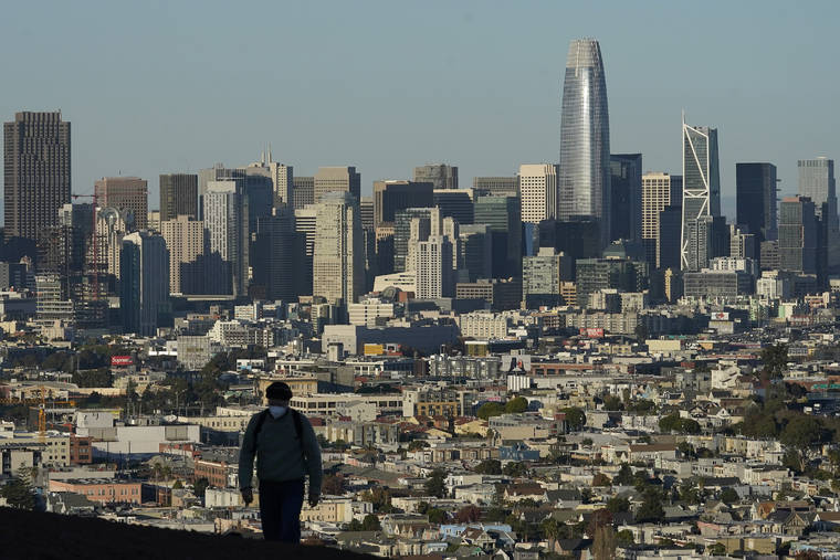 ASSOCIATED PRESS
                                A person wearing a protective mask walked in front of the skyline on Bernal Heights Hill, Dec. 7, during the coronavirus pandemic in San Francisco. California’s population has declined for the first time in its history.