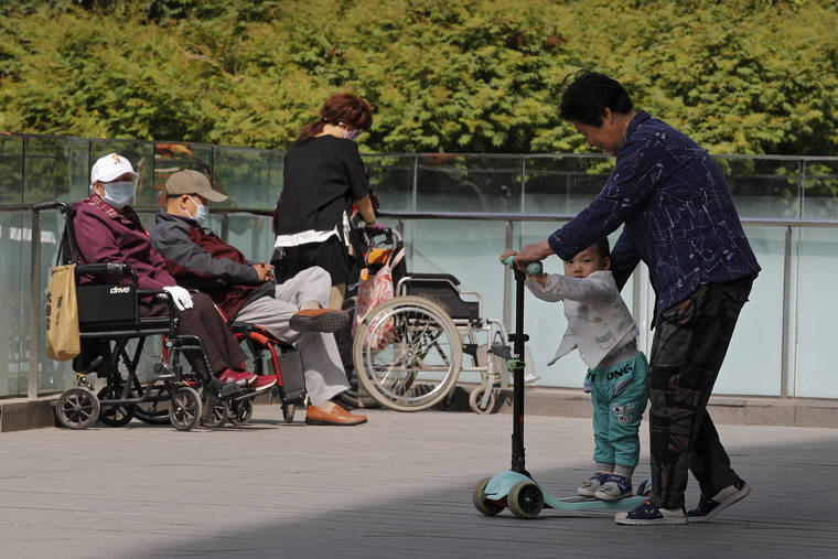 ASSOCIATED PRESS
                                A woman plays with a child near elderly people on wheelchairs sunbathing on a compound of a commercial office building in Beijing on Monday.