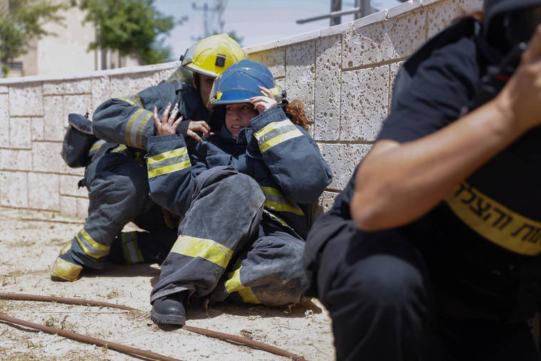 ASSOCIATED PRESS
                                Israeli firefighters take cover as a siren sounds a warning of incoming rockets fired from the Gaza strip, in the southern Israeli town of Ashkelon today.