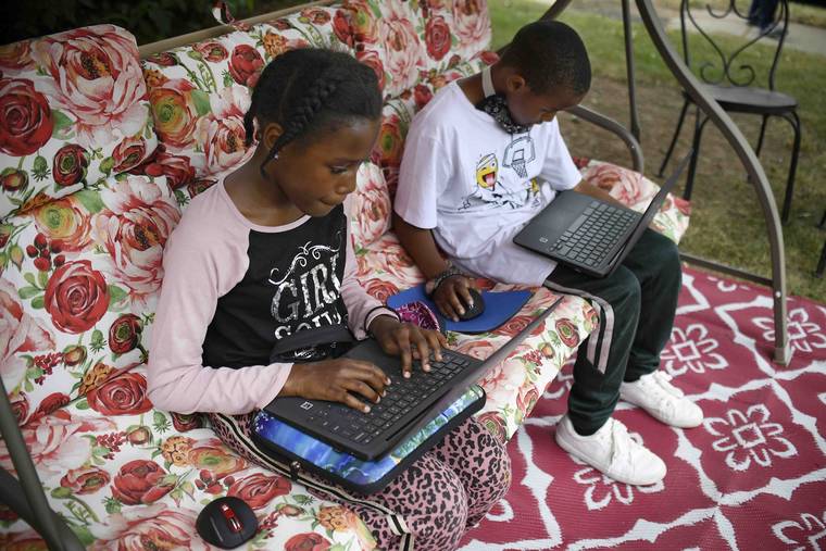 ASSOCIATED PRESS
                                Fourth-grader Sammiayah Thompson, left, and her brother, third-grader Nehemiah Thompson, worked outside, in June 2020, in their yard on laptops provided by their school system for distance learning in Hartford, Conn. Americans can begin applying for $50 off their internet bill, today, as part of an emergency government program to keep people connected during the pandemic.