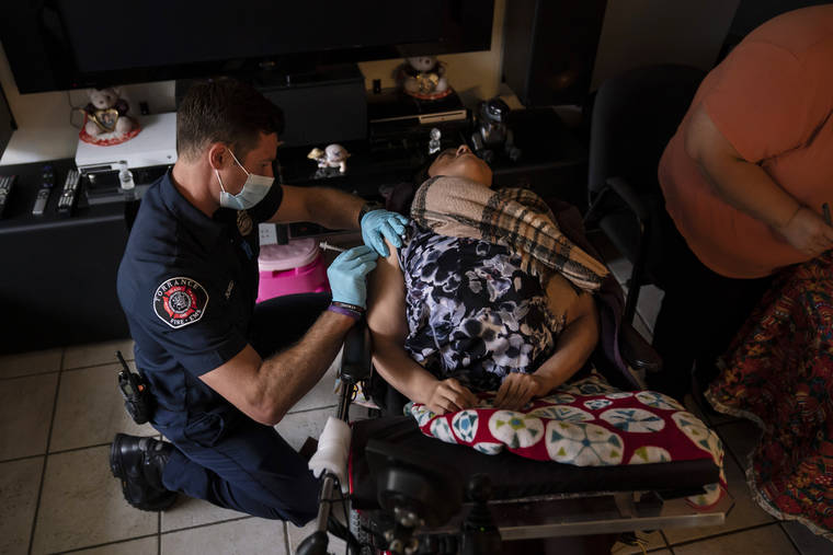 ASSOCIATED PRESS
                                Torrance firefighter Trevor Borello, left, administers the second dose of the Pfizer COVID-19 vaccine to Barbara Franco, who has muscular dystrophy, at her apartment in Torrance, Calif.
