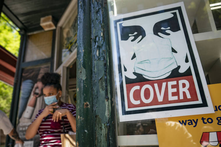 ASSOCIATED PRESS
                                A customer exits a corner market while wearing a protective mask in the retail shopping district of the SoHo neighborhood of Manhattan on Friday. New York Gov. Andrew Cuomo has yet to say whether he will change his state’s mask mandate in light of new federal guidance that eases rules for fully vaccinated people.