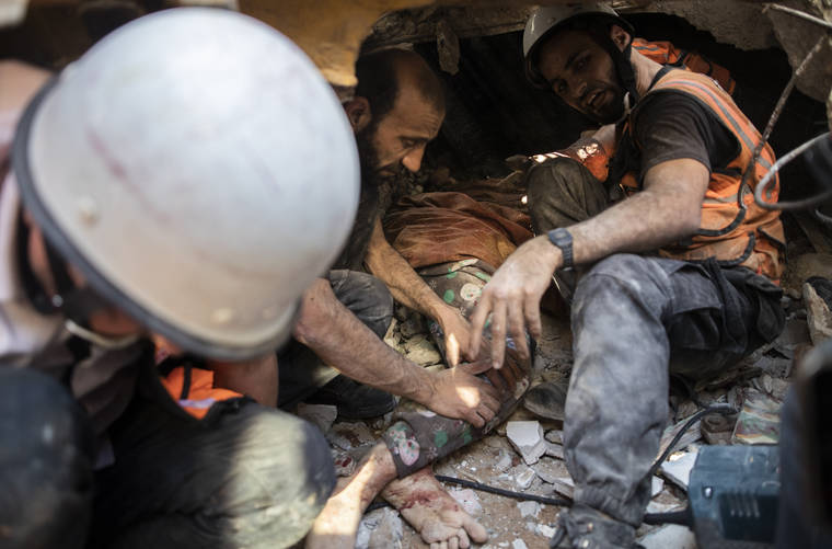 ASSOCIATED PRESS
                                Palestinian rescuers pull the body of a woman from under the rubble of a destroyed residential building following deadly Israeli airstrikes on Gaza City that flattened three buildings today.