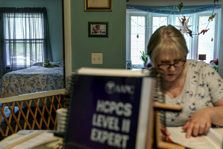 ASSOCIATED PRESS
                                Ellen Booth, 57, studied at her kitchen table to become a certified medical coder as her cat, Juji, sat on a bed behind her in Coventry, R.I., Monday. When the restaurant she worked for closed last year, Booth said it gave her “the kick I needed.”