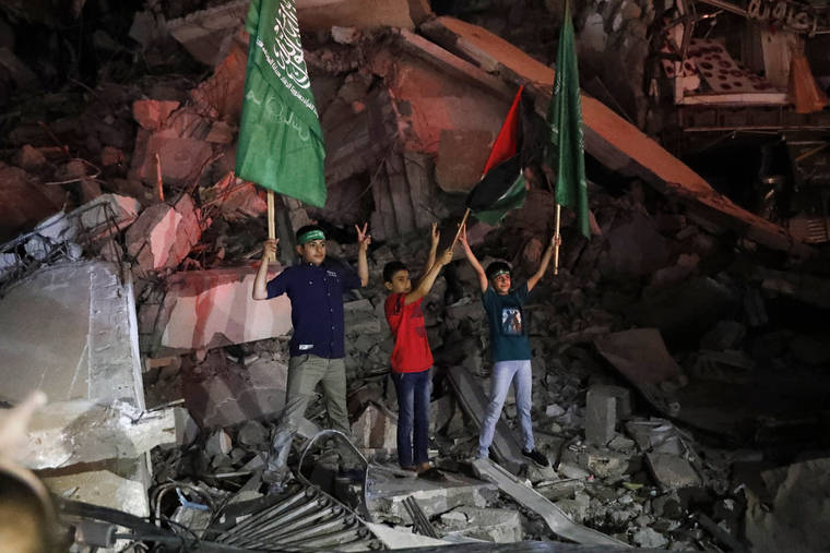 ASSOCIATED PRESS
                                Palestinian children wave green Hamas and their national flags as they stand on the rubble of a destroyed building while celebrating the cease-fire agreement between Israel and Hamas in Gaza City.