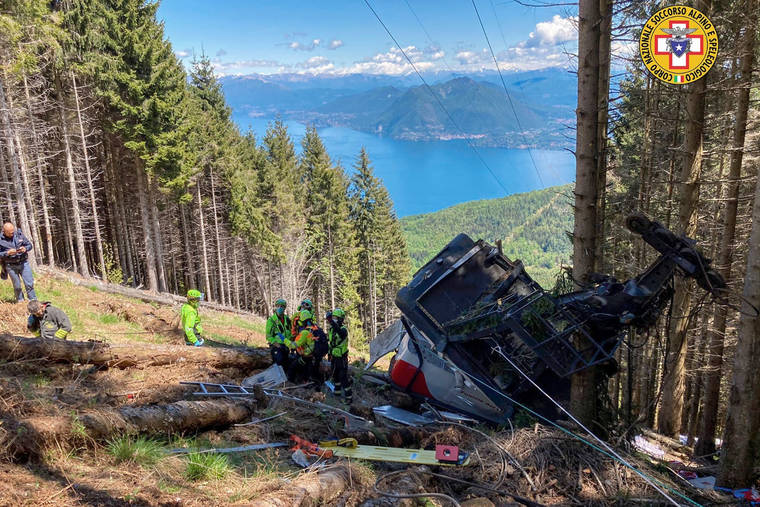 Rescuers work by the wreckage of a cable car after it collapsed near the summit of the Stresa-Mottarone line in the Piedmont region, northern Italy, Sunday, May 23, 2022. A mountaintop cable car plunged to the ground in northern Italy on Sunday, killing at least five people and sending at least three more to the hospital, authorities said. (Soccorso Alpino e Speleologico Piemontese via AP)