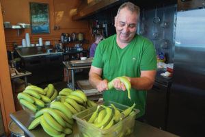 CRAIG T. KOJIMA / CKOJIMA@STARADVERTISER.COM
                                Koti Ramirez Baranda peels bananas in his Wat Get? shop, where he serves plates of the classic Puerto Rican food.