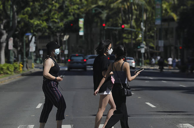 JAMM AQUINO / MAY 4
                                Pedestrians wearing masks walk on Kalakaua Avenue earlier this month in Waikiki. Gov. David Ige last week said the state’s mask mandate will remain in place despite updated CDC guidance that says fully vaccinated people can forego wearing a mask in most situations.