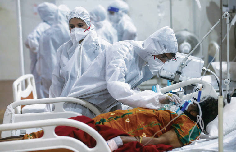 ASSOCIATED PRESS
                                A health worker tried to adjust the oxygen mask of a COVID-19 patient Thursday at the BKC field hospital in Mumbai, India.