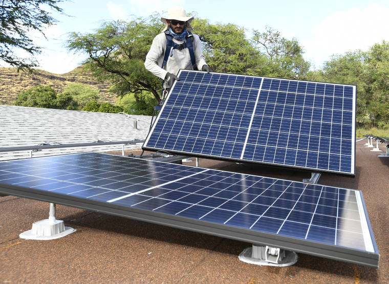 STAR-ADVERTISER / 2019
                                Marco Bernard puts into place one of the 33 solar panels on the roof of a solar electricity customer’s garage.