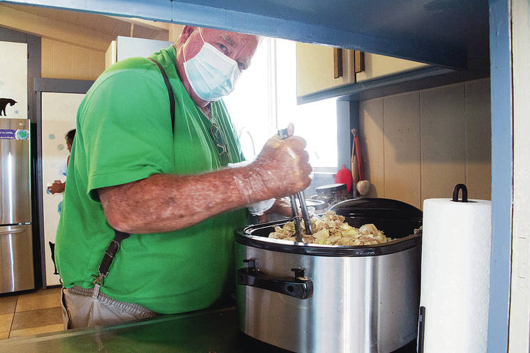 CRAIG T. KOJIMA / CKOJIMA@STARADVERTISER.COM
                                Mike Broderick mixes the kalua pig and cabbage that will be served to the needy.