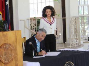 COURTESY PHOTO
                                Gov. David Ige signs a measure that designates Juneteenth as a day of remembrance as 2020 Miss Hawaii USA, Samantha Neylund, looks on.