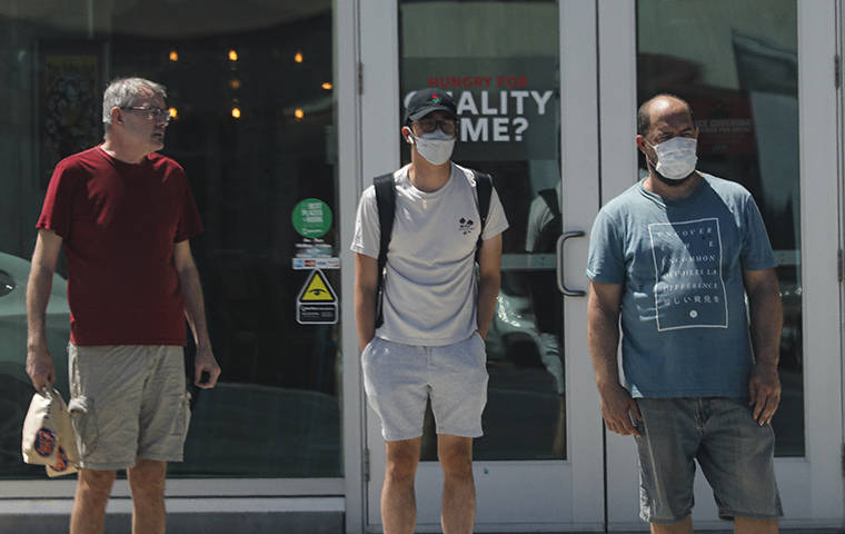 JAMM AQUINO / JUNE 30
                                Masked and unmasked pedestrians wait to cross University Avenue on June 30.