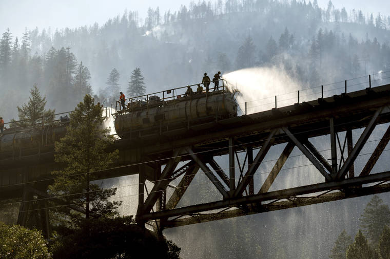 ASSOCIATED PRESS / JULY 16
                                Firefighters spray water from Union Pacific Railroad’s fire train while battling the Dixie Fire in Plumas National Forest, Calif.