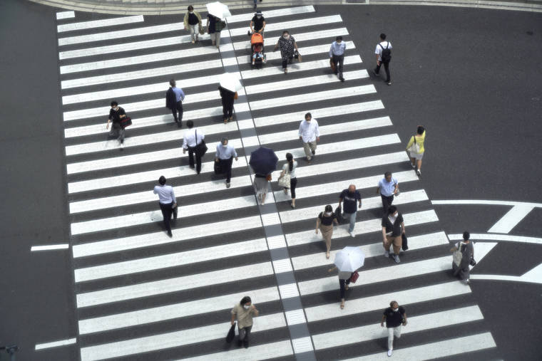 ASSOCIATED PRESS
                                People walk across a crossing near Tokyo Station in Tokyo on Thursday.