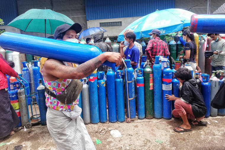 ASSOCIATED PRESS
                                A man carries an oxygen tank while walking past people waiting with oxygen tanks in need of refill outside the Naing oxygen factory at the South Dagon industrial zone in Yangon, Myanmar.
