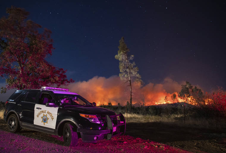 ASSOCIATED PRESS
                                A California Highway Patrol officer watches flames visible from the Zogg Fire near Igo, Calif., in Sept. 2020. Pacific Gas & Electric will face criminal charges because its equipment sparked the wildfire that killed four people and destroyed hundreds of homes, a Northern California prosecutor announced.