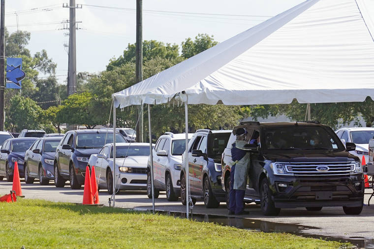 ASSOCIATED PRESS
                                Cars line up at Miami Dade College North campus’ COVID-19 testing site, Thursday, in Miami.