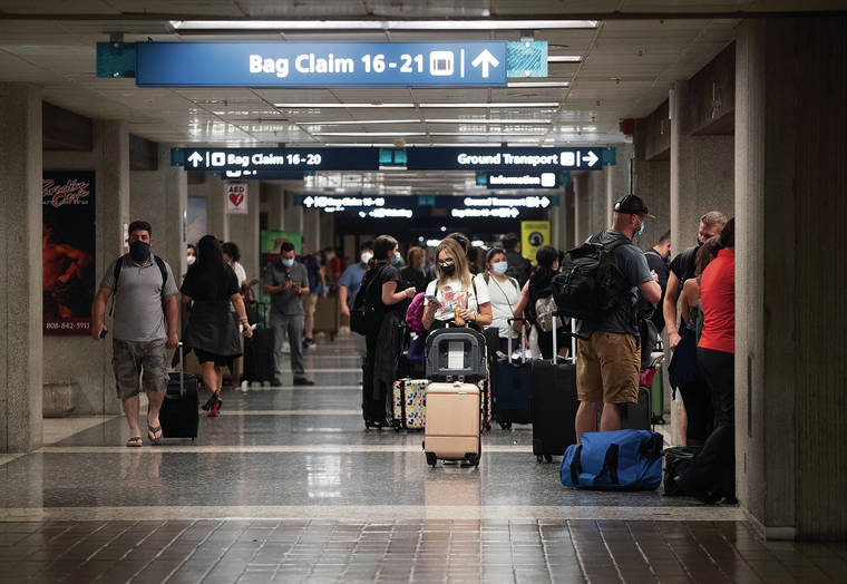 CINDY ELLEN RUSSELL / CRUSSELL@STARADVERTISER.COM
                                Travelers gathered in the Terminal 2 baggage claim area of Daniel K. Inouye International Airport on Friday.