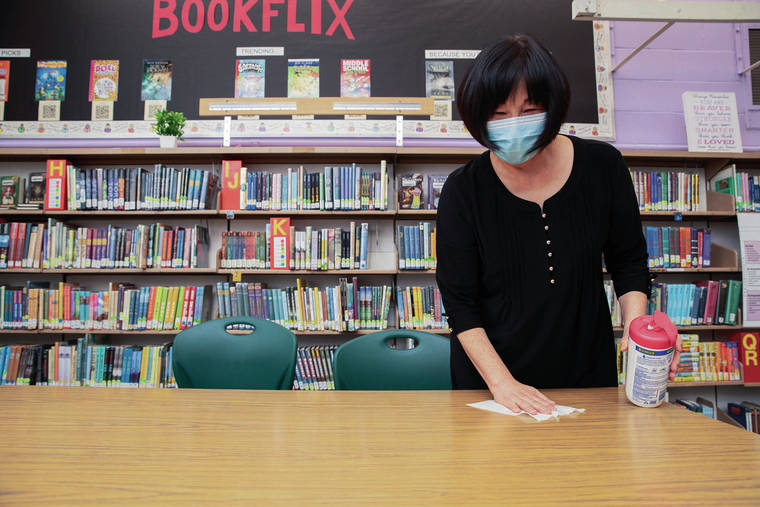 CINDY ELLEN RUSSELL / CRUSSELL@STARADVERTISER.COM
                                The state Department of Health recommends all teachers and students wear masks to school this year, regardless of their vaccination status. Above, Laurie Chang, curriculum coordinator and instructional coach for Aliiolani Elementary School, sanitizes a table in the school library, which will double for special classes.