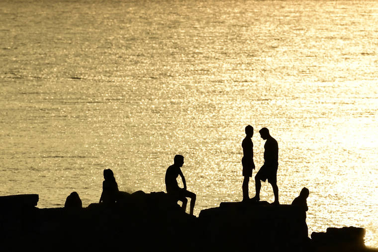 ASSOCIATED PRESS
                                People stand on rocks near a beach of Kavouri suburb, southwest of Athens, Greece, today.