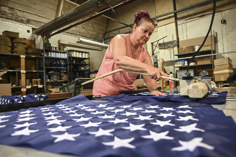 ASSOCIATED PRESS / JUNE 28
                                Debbie Wademan, production supervisor, cuts the stars to proper length to make American flags at North American Manufacturing in Scranton, Pa.