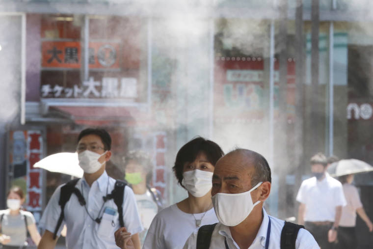 ASSOCIATED PRESS
                                People wearing face masks to protect against the spread of the coronavirus walked under a water mist in Tokyo, Thursday. New cases surge in Tokyo to record levels during the Olympic Games.