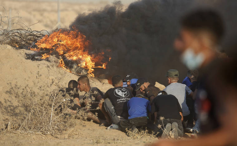 ASSOCIATED PRESS
                                Protesters take cover next to tires on fire near the fence of Gaza Strip border with Israel during a protest east of Khan Younis, southern Gaza Strip. Hundreds of Palestinians on Wednesday demonstrated near the Israeli border in the southern Gaza Strip, calling on Israel to ease a crippling blockade days after a similar gathering ended in deadly clashes with the Israeli army.
