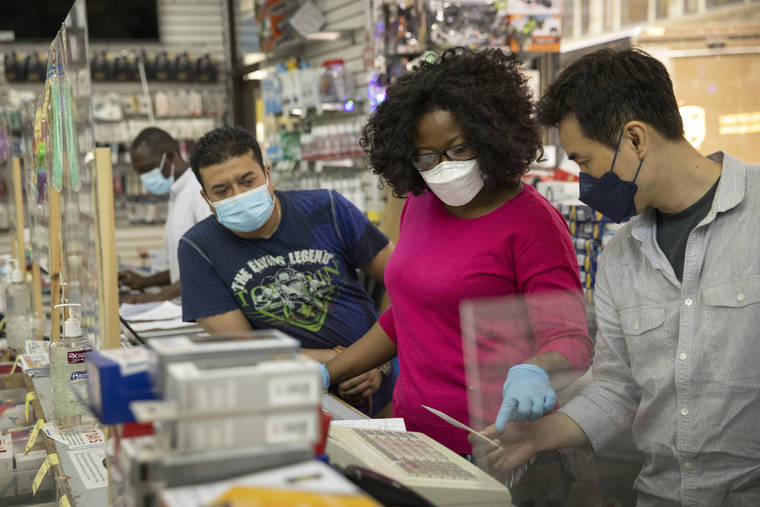 NEW YORK TIMES
                                Employees wear masks at an electronics store in Manhattan on Wednesday.