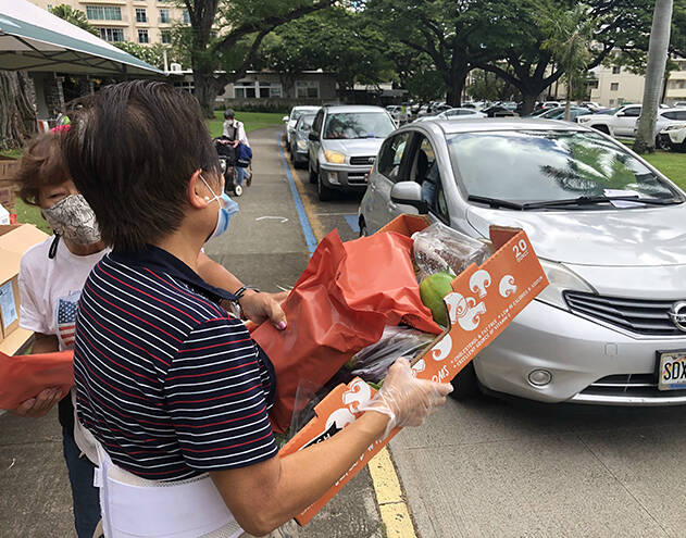 CRAIG T. KOJIMA / CKOJIMA@STARADVERTISER.COM
                                Fanny Yeung hands out food at Central Union Church of Honolulu which observed one year of distributing food to residents. About 500 people received 22 pounds of food each at the event on Wednesday. The devastating economic effects of the coronavirus pandemic have greatly increased food insecurity throughout the islands.