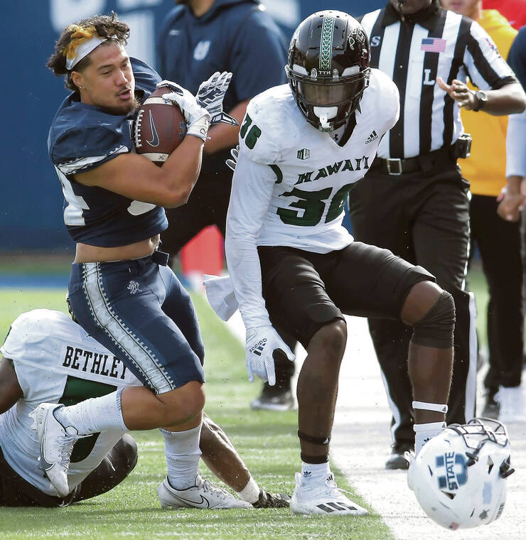 ELI LUCERO / THE HERALD JOURNAL VIA ASSOCIATED PRESS
                                Utah State running back Elelyon Noa lost his helmet after fighting through a pair of Hawaii tacklers, defensive backs Khoury Bethley (5) and Solo Turner (36), during the second quarter Saturday in Logan, Utah.