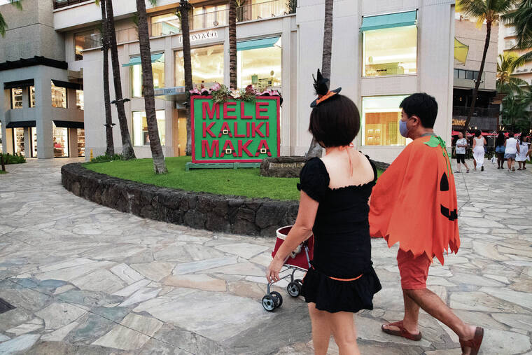 CINDY ELLEN RUSSELL / CRUSSELL@STARADVERTISER.COM
                                After two years of lagging sales, retailers cannot wait for holiday buyers. On Halloween, Christmas decorations were already up in Waikiki as a couple dressed in costumes walked past a festive sign at the Royal Hawaiian Center.