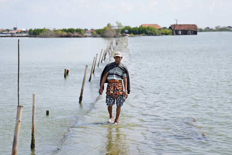 ASSOCIATED PRESS
                                A man walked on a pathway that was partially submerged due to the rising sea levels in the village of Sidogemah, Central Java, Indonesia, Sunday. World leaders are gathered in Scotland at a United Nations climate summit, known as COP26, to push nations to ratchet up their efforts to curb climate change.