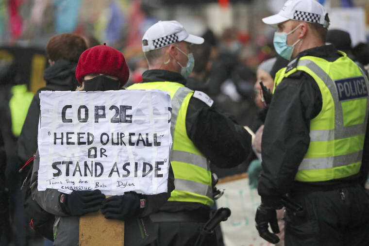 ASSOCIATED PRESS
                                A climate activist holds a placard next to police officers near the venue for the COP26 U.N. Climate Summit in Glasgow, Scotland.