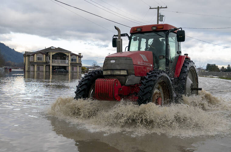 DARRYL DYCK/THE CANADIAN PRESS VIA AP
                                A tractor drives over a flooded road following heavy rain and mudslides in Abbotsford, British Columbia.