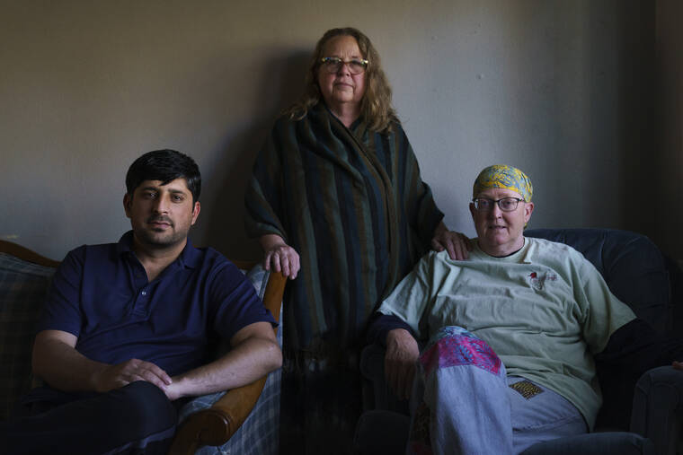 ASSOCIATED PRESS
                                Ihsanullah Patan, left, a horticulturist and refugee from Afghanistan, sits for a portrait with Caroline Clarin, right, whom he worked with in Afghanistan, and her wife, Sheril Raymond, at his home in Fergus Falls, Minn.