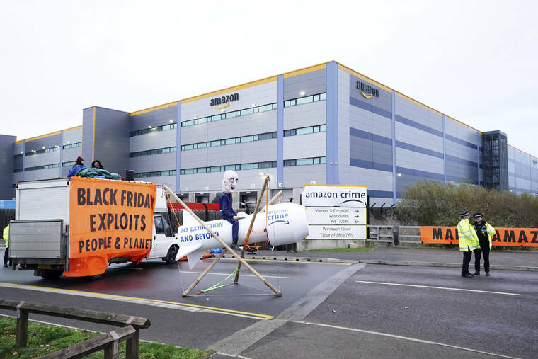IAN WEST/PA VIA AP
                                Activists from Extinction Rebellion block the entrance to the Amazon fulfilment centre, preventing lorries from entering or leaving on Black Friday, the global retail giant’s busiest day of the year, in Tilbury, England. The group has targeted Amazon sites in Doncaster, Darlington, Dunfremline, Newcastle, Manchester, Peterborough, Derby, Coventry, Rugeley, Dartford, Bristol, Tilbury and Milton Keynes.