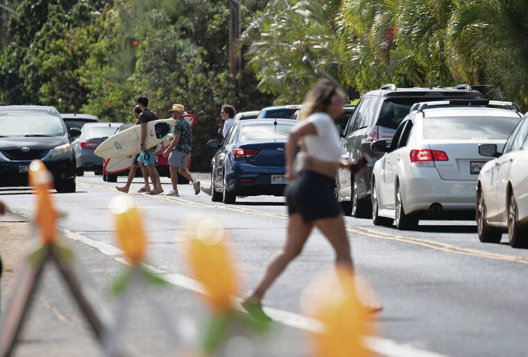CINDY ELLEN RUSSELL / CRUSSELL@STARADVERTISER.COM
                                Barriers were installed last week along the mauka shoulder of Kamehameha Highway across Laniakea to improve safety and traffic flow. People crossed the busy roadway on Friday.